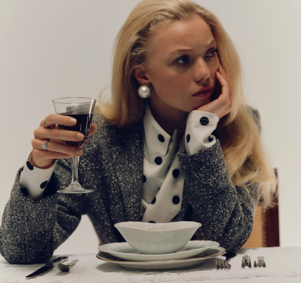 A woman holds a glass in silence, evoking holiday blues and emotions that don’t always match the festive season.